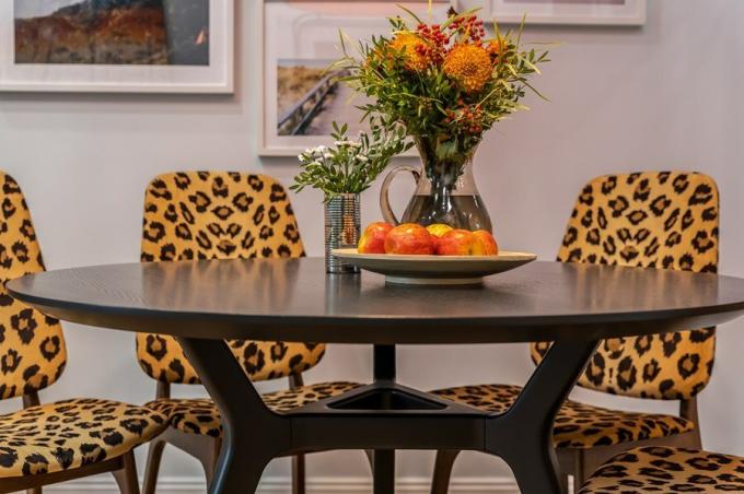 Cerah, ruang makan eksotis menetapkan suasana hati warna cerah dengan ceria pinggiran sutra. Di bawah kubah ini berdiri sebuah meja bundar kayu veneer gelap walnut.
