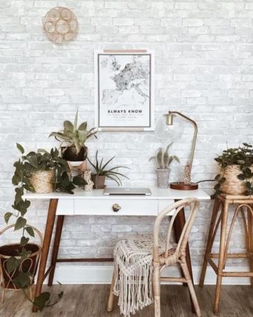 Kantor rumah boho yang apik dengan meja kayu retro, permadani boho, seni dinding, banyak tanaman hias: kaktus dan sukulen